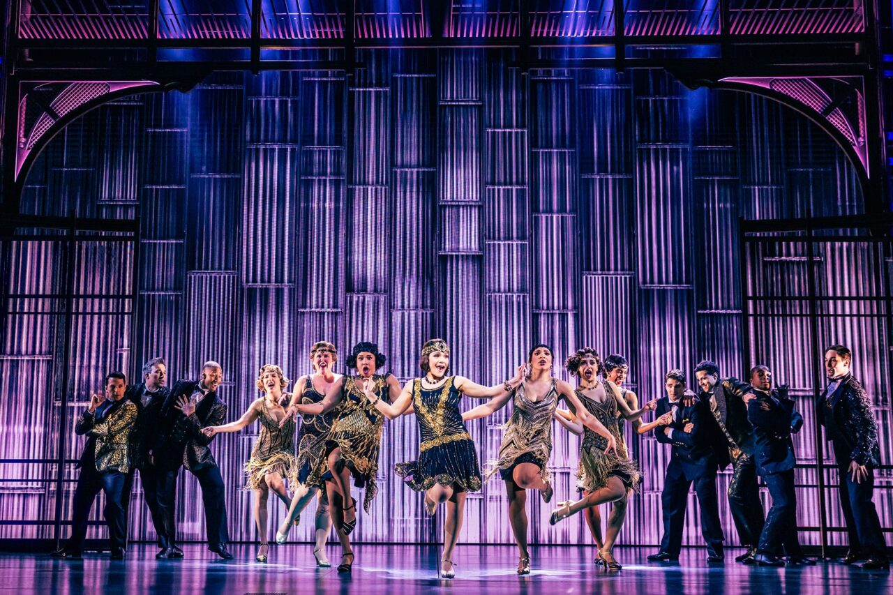 Dancers from the cast of The Great Gatsby performing against a purple stage set