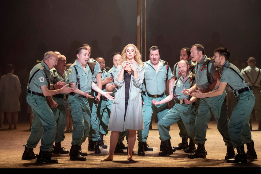 The cast of Carmen on stage at the London Coliseum. Carmen standing centre surrounded by male characters