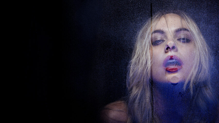 Close up of blonde woman behind steamy glass